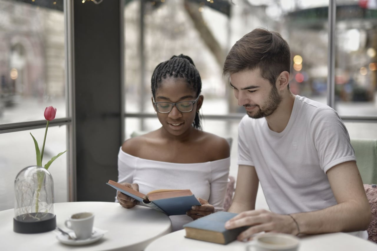 Personas conversando alrededor de libros y café, imagen ilustrativa