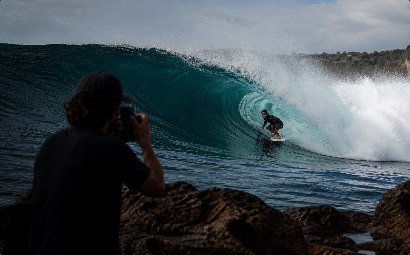 A surfer takes part in a real session while a creator documents the experience